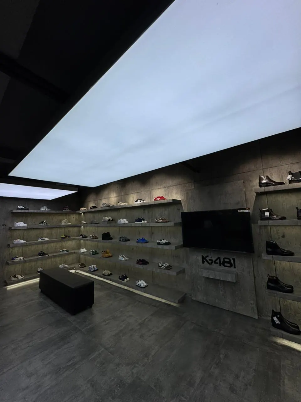 The AG 481 wall — sneakers lit along raw concrete shelving